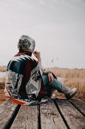 Alpaca poncho with native Inca pattern in red, blue, and beige colors. Fringed edges and geometric designs.
