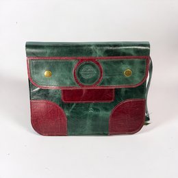  Handmade cowhide leather clutch bag in a bold green and red color scheme, featuring a unique patchwork design with circular accents.