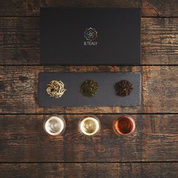 Luxurious wooden tea box with premium tea varieties, including black, green, and herbal teas, presented on a dark slate background.
