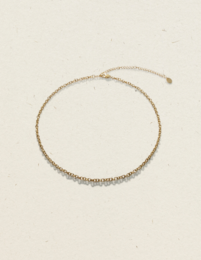 Gold-toned charm necklace with a delicate chain and a thorn-shaped pendant.