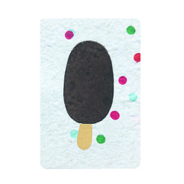 A frozen ice cream treat on a stick, with a dark brown ice cream scoop and a wooden stick. The background is a textured white surface with colorful polka dots.