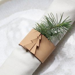 Set of 4 natural leather napkin rings in the shape of Christmas trees. Ideal for holiday table settings.