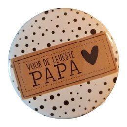 A round metal button opener with the text "Voor de liefste papa" (For the dearest dad) printed on a leather-like label. The button opener has a polka dot pattern in the background.