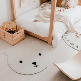 Soft, plush, white bear-shaped rug for children's bedroom. Made of washable material, suitable for kids' play area.