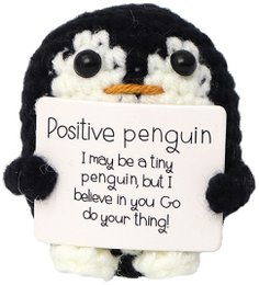  A black and white plush penguin toy with a positive message on a sign it is holding. The penguin has a round, cute design with large eyes and a small beak.