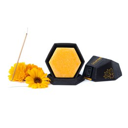 A solid, hexagonal body butter in a vibrant yellow color, made with natural ingredients like calendula flowers.