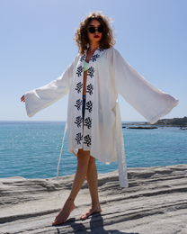  White cotton bathrobe with floral embroidery, perfect for beach cover-up or loungewear. Loose, flowing design with bell sleeves.