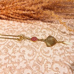 Bohemian-style hair pin with gilded brass beads, seashell, and turquoise accents. Ideal for adding a touch of chic to any hairstyle.