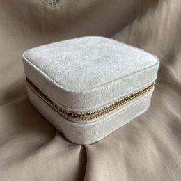  Beige square jewelry box with mirror. Made of soft, plush material. Features a zipper closure for secure storage of jewelry and other small items.
