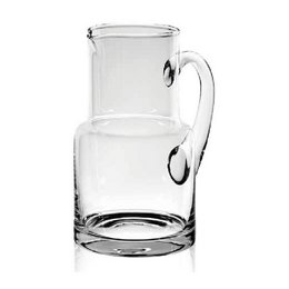 Glass pitcher with a tall, cylindrical shape and a handle. The pitcher is made of clear glass and has a simple, minimalist design.
