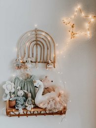 Rattan rainbow hook rack for kids' wardrobes, featuring a curved rattan design with multiple hooks for hanging clothes, accessories, or decor. The neutral color palette and natural materials create a warm, cozy aesthetic suitable for a child's bedroom or nursery.