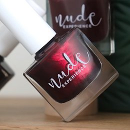 Vibrant red nail polish with a metallic finish and the "Nude Experience" logo.