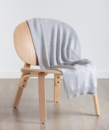 Grey throw blanket made of soft, cozy material. Rectangular shape with a simple, minimalist design. Suitable for use as a decorative accent or for keeping warm.