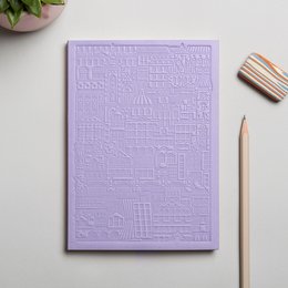 A notebook with a textured cover in various colors including blue, yellow, rust, green, concrete, and lavender. The cover features an abstract geometric pattern.