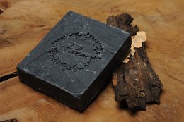 Black charcoal soap bar with nigella seeds. Rectangular shape, dark gray color, natural ingredients.