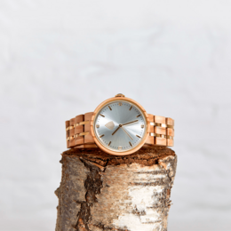 A handmade vegan wood watch with a teak wood case and silver-toned dial. The watch features a simple, minimalist design with a round case shape.