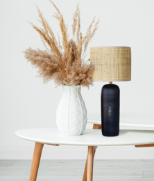 Tall, cylindrical table lamp with a raffia and ceramic base, featuring a neutral color palette and natural materials.