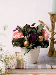 Dried flowers botanical arrangement, pink roses, dark purple blooms, green foliage, white ceramic vase, table décor.