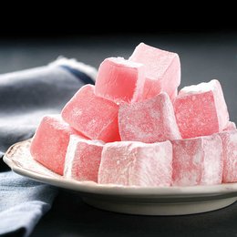 Pink, soft, chewy Turkish delight candies on a plate.