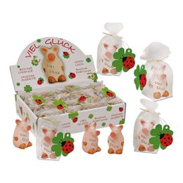  A small, clay figurine of a lucky pig standing upright. The pig has a white body with pink accents and is holding a four-leaf clover. The product is part of a set of similar figurines.