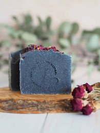 Charcoal black soap bar with dried rose petals, a natural and organic skincare product.