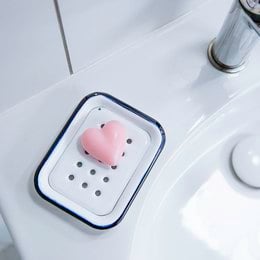 Rectangular enamel soap dish in a plain white and black design, with a perforated surface for drainage.