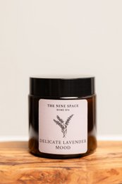 Delicate lavender scented candle in a glass jar with a black label.