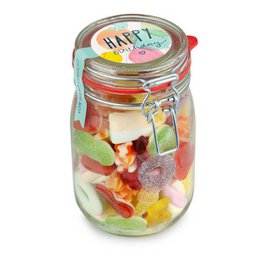 Colorful assortment of sweet candies in a glass jar with a "Happy Birthday" label, including gummy bears, jelly candies, and other festive treats.