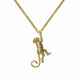 A gold-colored hanging monkey charm necklace with a satellite-shaped pendant.