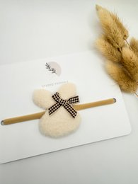  Soft, plush hairband with a black and white checkered bow accent. Suitable for young girls.