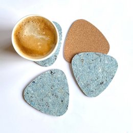 Set of 4 coasters made from plectrum-shaped cork material, with a natural, textured surface and blue-green color.