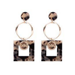 Gold-coated leopard print stud earrings with circular pendant detail.