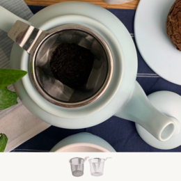 A white ceramic teapot with a built-in infuser for brewing loose leaf tea. The teapot has a simple, modern design and includes a matching brew mug.