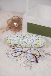  Glasses case with floral pattern, round brown glasses, and a pink case. The glasses case is 16x3.5 cm in size and is part of the Isabelle Rose collection.