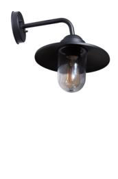 Black metal wall-mounted outdoor light fixture with glass shade. Provides illumination for an outdoor seating area with a stone wall, potted plants, and a small table and chairs.