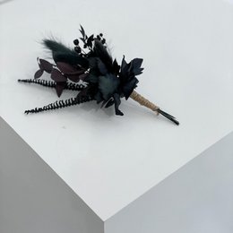 Black brooch with dried flowers and feathers, suitable for formal occasions.