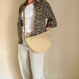 Tan cross-body bag with Aztec-inspired design, featuring a wide strap and a flap closure. Made of durable material, suitable for everyday use.