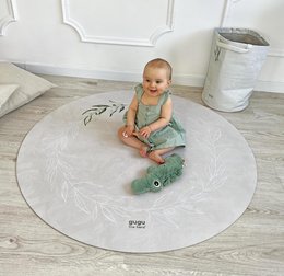 Round, olive-colored playmat with leaf and floral designs. Made of natural rubber for a soft, comfortable surface.
