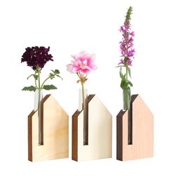 A wooden vase with a tall, cylindrical shape and a floral arrangement featuring pink and purple flowers. The vase appears to be made of a light-colored wood, possibly pine or poplar.