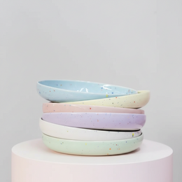 Set of 6 round, low pasta plates in pastel colors with speckled patterns.