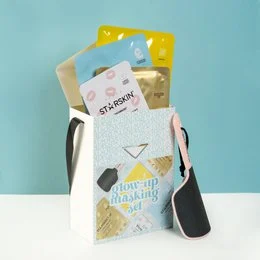 A glow-up masking set containing various beauty products in a white and yellow gift box.