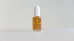 Amber-colored face oil in a glass bottle with a dropper. The oil appears to be a natural, organic product.