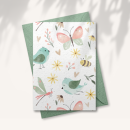 A nature-themed greeting card with a paper envelope. The card features colorful illustrations of flowers, butterflies, and bees, indicating it is a nature-themed card. The envelope is a light green color.