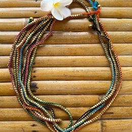 Handmade Dokra necklace with multiple strands of colorful beads in various shapes and sizes, including round, oval, and cylindrical beads in shades of orange, pink, blue, green, black, and purple. The necklace features a floral accent and appears to be a unique, artisanal piece.
