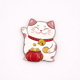 A white and red ceramic figurine of a lucky cat, also known as a Maneki-neko, a popular Japanese symbol of good fortune. The cat has a raised paw and is holding a gold coin.