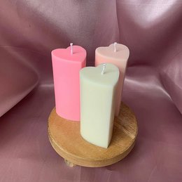 Pillar candles in various pastel colors including pink, beige, and green. The candles are heart-shaped, creating a romantic and decorative aesthetic. These candles would be suitable for home decor, special occasions, or as gifts.