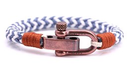 Nautical-inspired woven bracelet in white and navy blue with copper-colored metal clasp and accent.