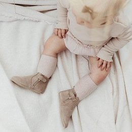 Taupe suede baby Chelsea boots with flower edge detail. Ankle-high style with elastic side panels for easy on and off. Durable rubber sole provides traction and support.