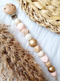 Pacifier clip with beads in shades of pink, gold, and white. Features a mix of round and irregular shaped beads for a unique, stylish design.
