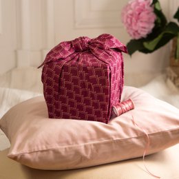  Burgundy wrapping paper with a repeating geometric pattern of arches or scallops. The fabric has a soft, textured appearance and would be suitable for gift wrapping, crafting, or home decor.